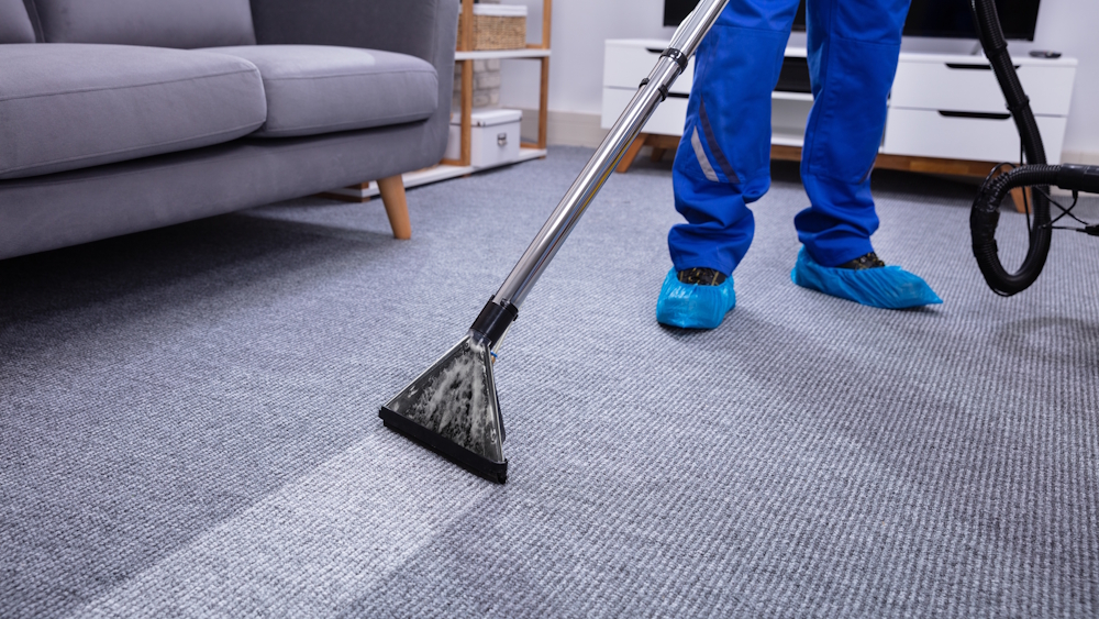 A man using an extraction cleaning machine on a carpet.