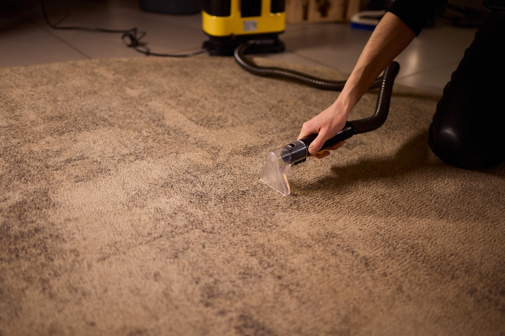 A man using a carpet cleaning machine on a rug